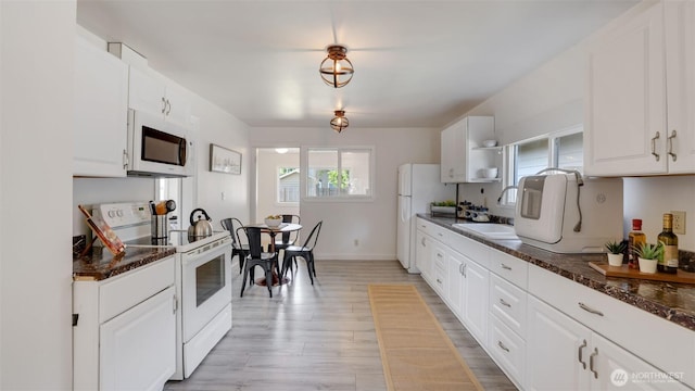 kitchen with white appliances, a sink, healthy amount of natural light, and light wood finished floors