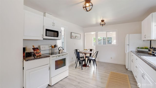 kitchen featuring white appliances, white cabinetry, light wood-type flooring, baseboards, and dark countertops