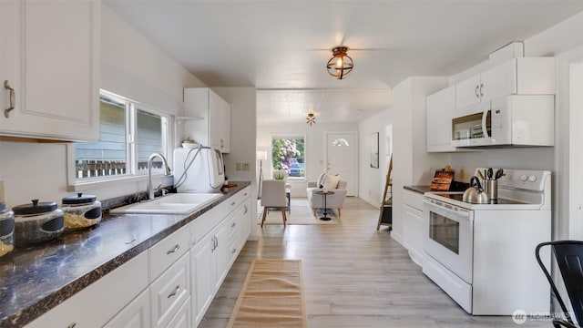 kitchen with white appliances, a sink, and dark countertops
