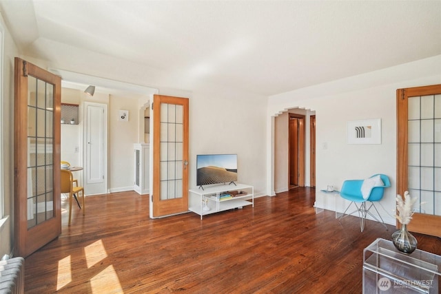 living room with wood finished floors, french doors, baseboards, and radiator heating unit