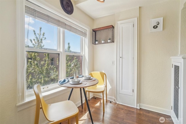 dining space with wood finished floors, a textured wall, and baseboards