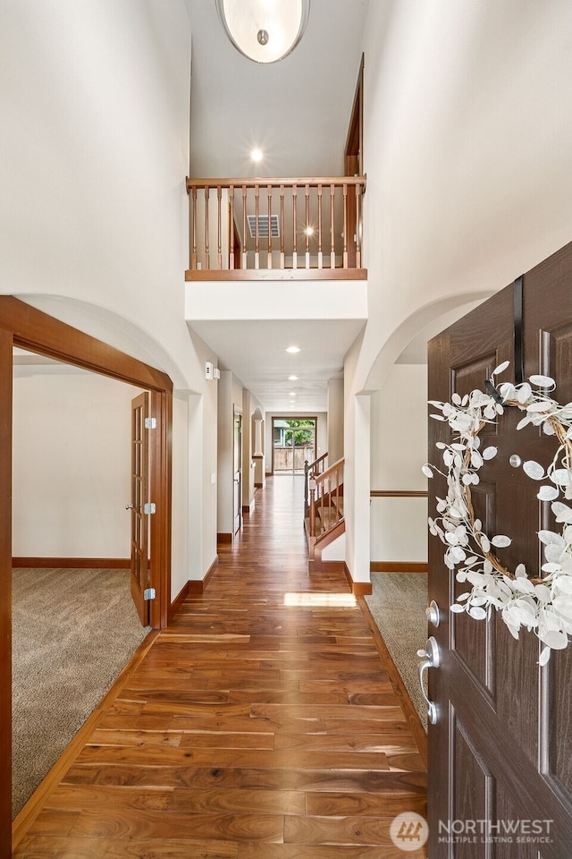 13809 172nd Pl E, Puyallup, WA 98374 - foyer entrance with arched walkways, wood finished floors, stairs, a high ceiling, and baseboards