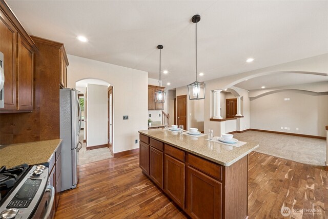 13809 172nd Pl E, Puyallup, WA 98374 - kitchen with arched walkways, stainless steel appliances, dark wood-style floors, brown cabinetry, and recessed lighting