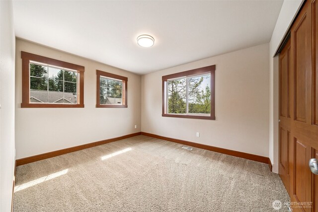 13809 172nd Pl E, Puyallup, WA 98374 - unfurnished bedroom featuring baseboards, a closet, multiple windows, and carpet