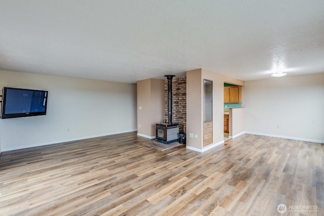 1068 Vista Del Monte, Camano Island, WA 98282 - unfurnished living room with light wood-style flooring, a wood stove, a textured ceiling, and baseboards