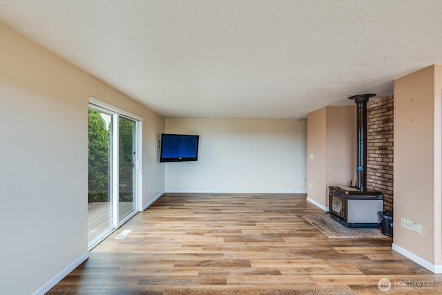 1068 Vista Del Monte, Camano Island, WA 98282 - unfurnished living room with a wood stove, wood finished floors, and baseboards