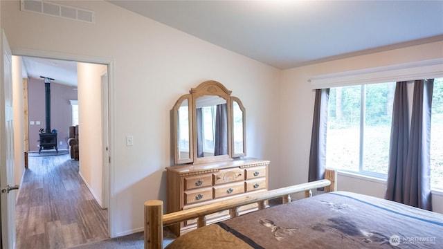 bedroom featuring baseboards, a wood stove, and wood finished floors