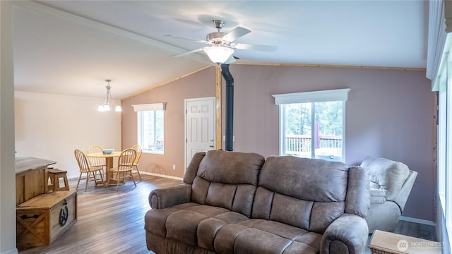 living room with wood finished floors, baseboards, a ceiling fan, lofted ceiling, and a wood stove