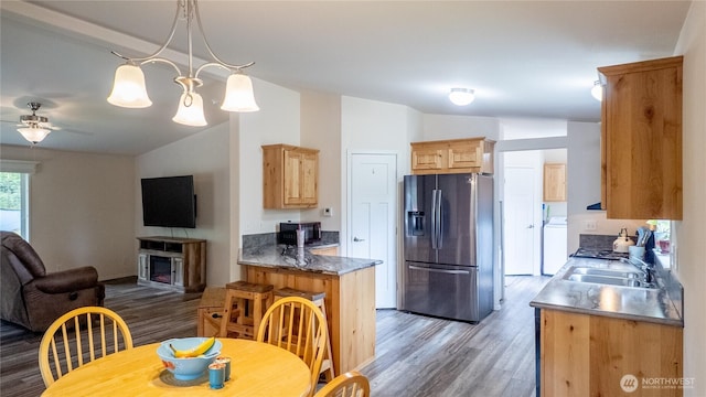 kitchen featuring stainless steel refrigerator with ice dispenser, open floor plan, vaulted ceiling, light wood-type flooring, and a fireplace