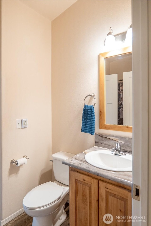 bathroom featuring vanity, toilet, baseboards, and wood finished floors