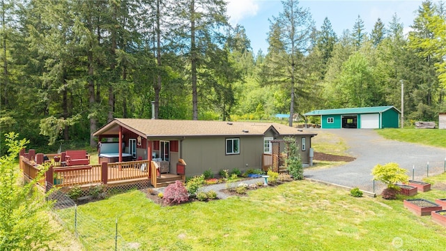 ranch-style house featuring a hot tub, a front lawn, an outbuilding, a vegetable garden, and a detached garage