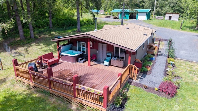 wooden terrace featuring a hot tub, an outdoor structure, and a yard