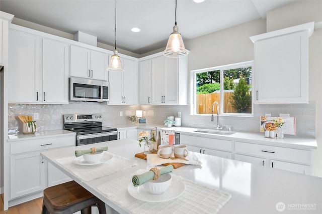 2900 NE 5th Pl, Renton, WA 98056 - kitchen featuring stainless steel appliances, a sink, light countertops, a kitchen bar, and recessed lighting