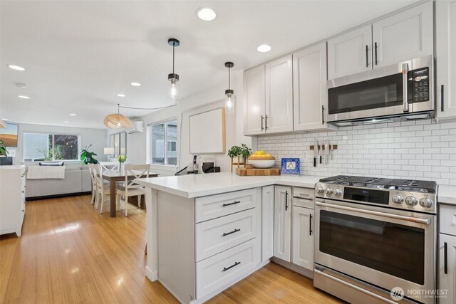 kitchen with stainless steel appliances, open floor plan, a peninsula, tasteful backsplash, and light countertops
