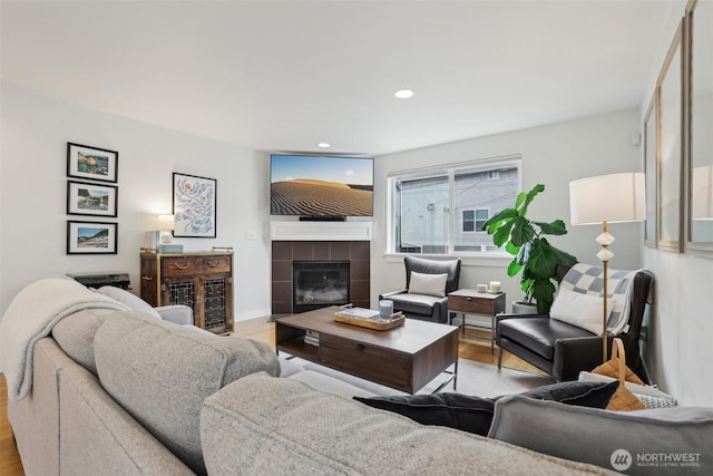 living area featuring wood finished floors, a tiled fireplace, and recessed lighting