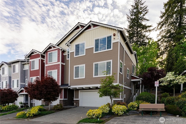 townhome / multi-family property featuring board and batten siding, a garage, asphalt driveway, and stone siding