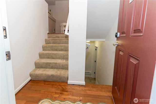 entryway with wood finished floors, stairway, a baseboard heating unit, and baseboards