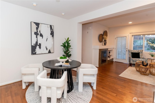 dining area featuring wood finished floors, a fireplace, recessed lighting, and baseboards