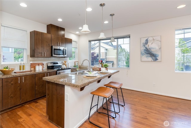 kitchen with appliances with stainless steel finishes, a sink, light wood-style flooring, plenty of natural light, and recessed lighting