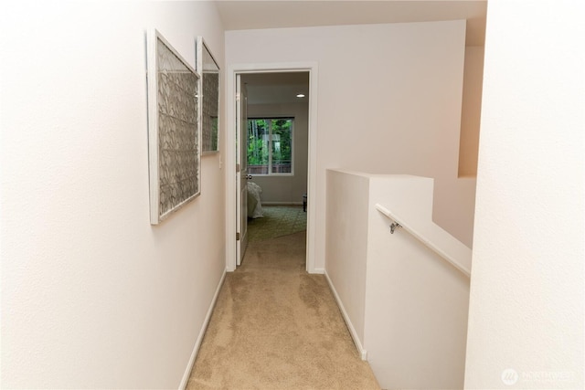 corridor with an upstairs landing, carpet flooring, and baseboards