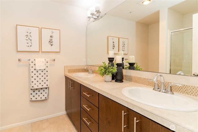 bathroom with double vanity, a shower with door, baseboards, and tile patterned floors