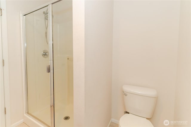 bathroom featuring baseboards, a stall shower, and toilet