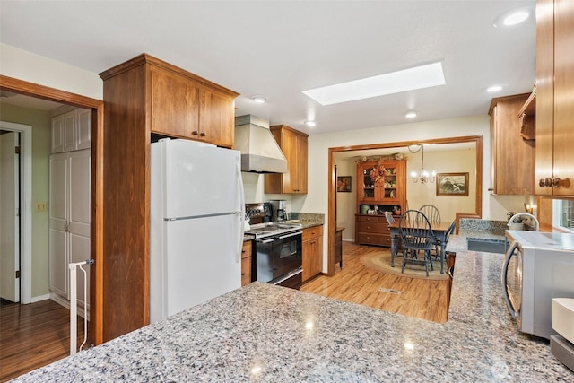 2124 213th Street Ct E, Spanaway, WA 98387 - kitchen featuring black electric range oven, custom exhaust hood, freestanding refrigerator, a sink, and a skylight