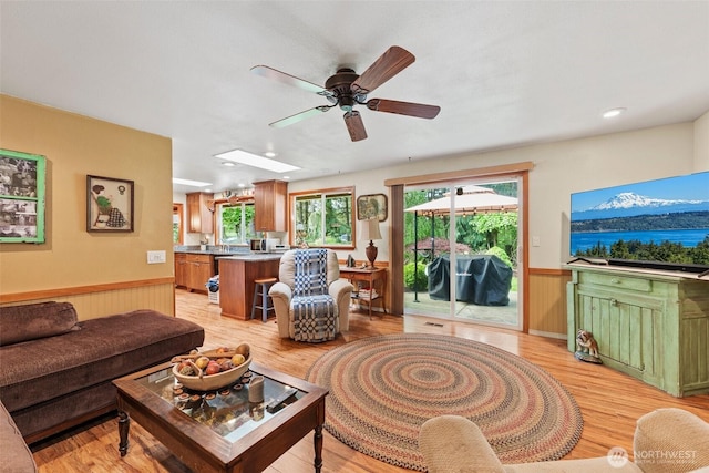 2124 213th Street Ct E, Spanaway, WA 98387 - living room featuring a ceiling fan, wainscoting, light wood finished floors, and a skylight