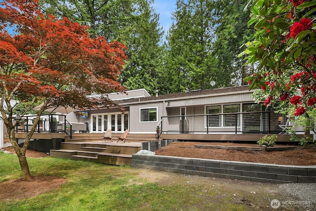 view of front facade featuring a wooden deck, a front lawn, and a shingled roof