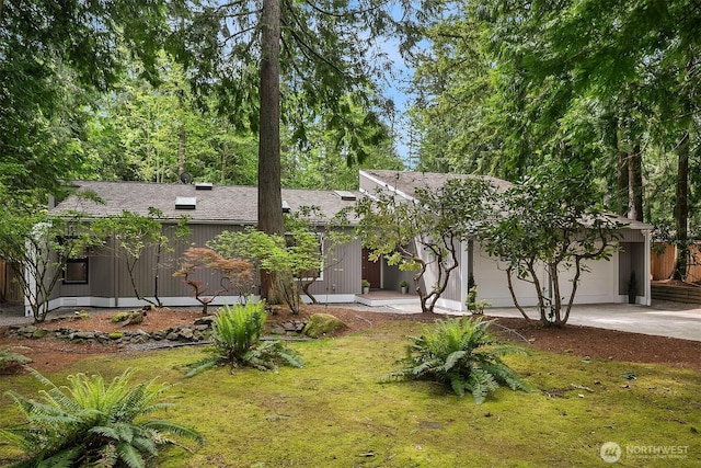 view of front facade with concrete driveway, a garage, and a front lawn