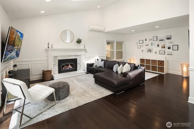 living area featuring a wall mounted air conditioner, a decorative wall, dark wood finished floors, recessed lighting, and a warm lit fireplace