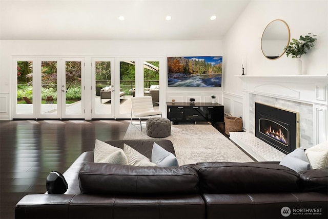 living room featuring a high end fireplace, a decorative wall, recessed lighting, lofted ceiling, and wainscoting