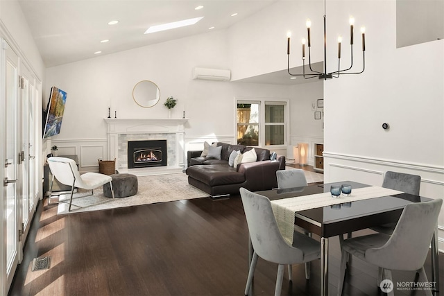 dining space featuring a wall mounted AC, wood finished floors, recessed lighting, a decorative wall, and a chandelier