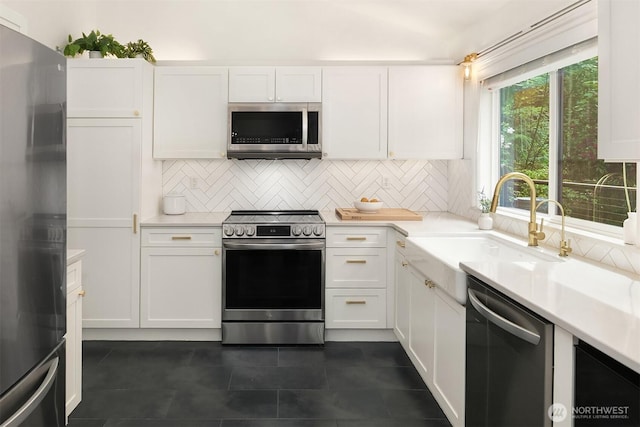 kitchen featuring stainless steel appliances, a sink, tasteful backsplash, and white cabinetry