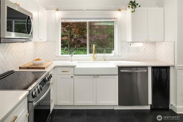kitchen with stainless steel appliances, dark tile patterned floors, and white cabinetry