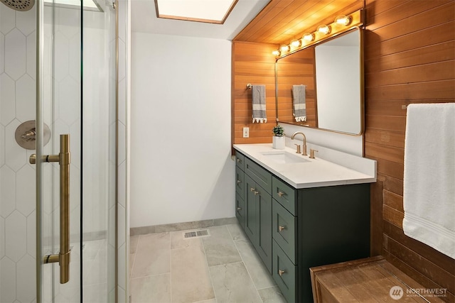 full bath with wooden walls, a stall shower, baseboards, vanity, and tile patterned flooring