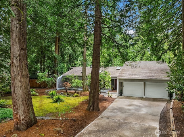 view of front of property featuring a garage, a shingled roof, and concrete driveway