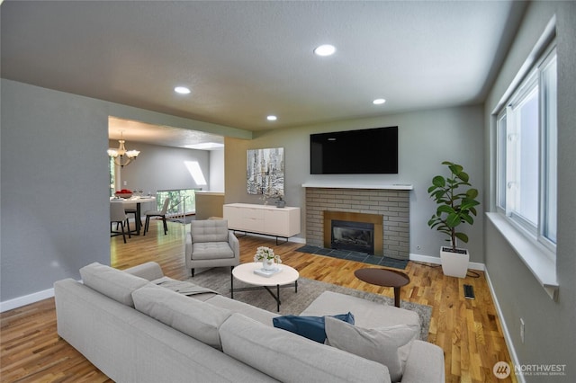 10910 114th Ave SW, Tacoma, WA 98498 - living room with a chandelier, a brick fireplace, recessed lighting, baseboards, and wood finished floors