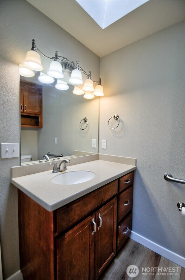 10910 114th Ave SW, Tacoma, WA 98498 - bathroom featuring wood finished floors, vanity, a skylight, baseboards, and toilet