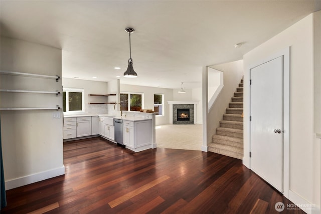 kitchen featuring a peninsula, a fireplace, dishwasher, open shelves, and open floor plan