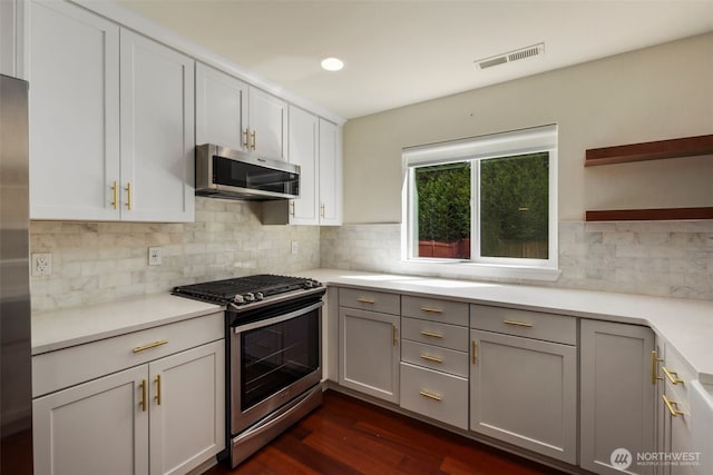 kitchen with stainless steel appliances, open shelves, dark wood-style floors, decorative backsplash, and light countertops