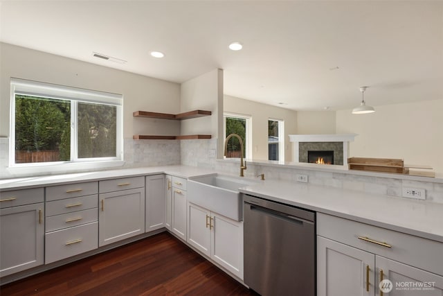 kitchen featuring stainless steel dishwasher, a sink, open shelves, light countertops, and decorative backsplash
