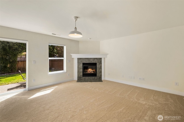 unfurnished living room featuring carpet flooring, a tile fireplace, and baseboards