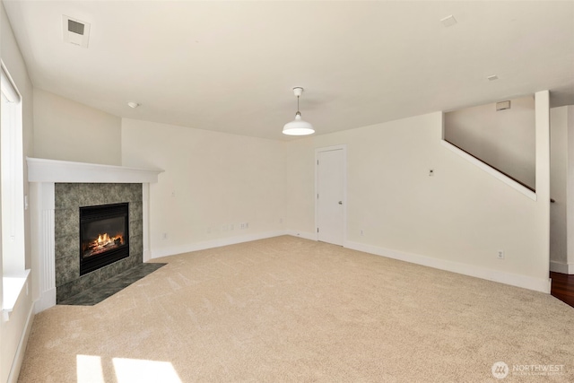 unfurnished living room with carpet flooring, a tiled fireplace, and baseboards