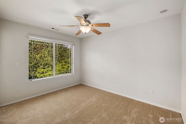 carpeted spare room featuring ceiling fan and baseboards