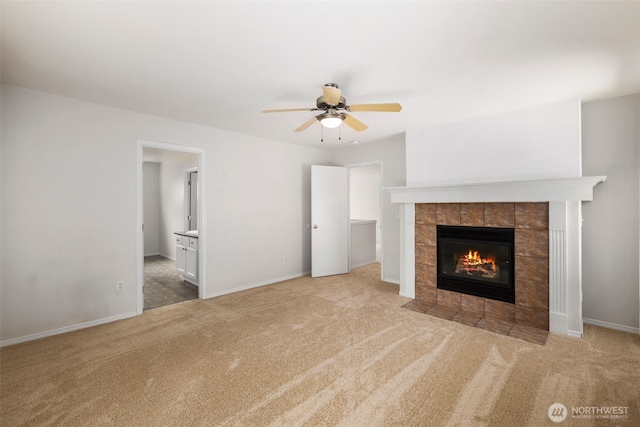 unfurnished living room with carpet floors, ceiling fan, a tile fireplace, and baseboards