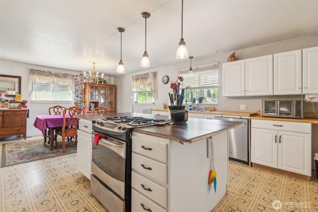 12623 Douglas Rd, Yakima, WA 98908 - kitchen with appliances with stainless steel finishes, white cabinetry, hanging light fixtures, a kitchen island, and a chandelier