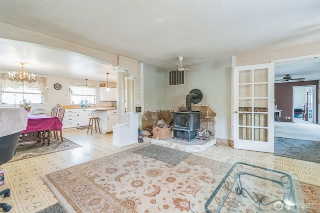12623 Douglas Rd, Yakima, WA 98908 - living area featuring ceiling fan, a wood stove, ornate columns, light floors, and a chandelier