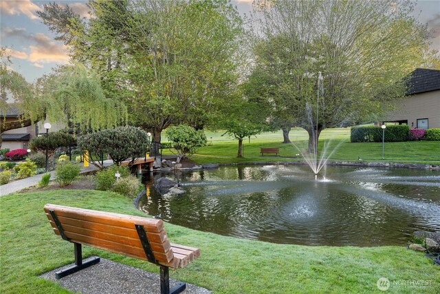 view of property's community with a lawn and a water view