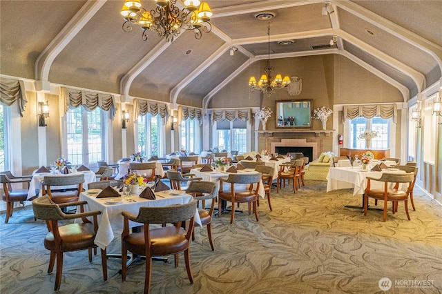 dining room featuring a chandelier, healthy amount of natural light, carpet, and high vaulted ceiling